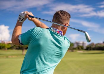 Male golfer taking a swing on a sunny golf course in Boca Raton, Florida.