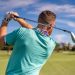 Male golfer taking a swing on a sunny golf course in Boca Raton, Florida.