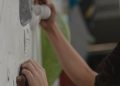 Close-up of hands gripping holds on an indoor climbing wall during bouldering session.