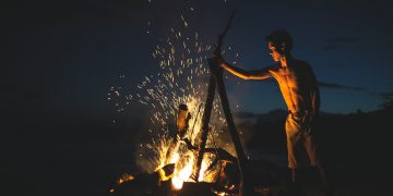 topless man lighting bonfire